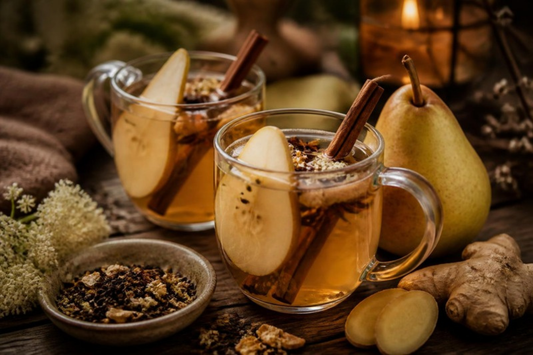 two mugs of spiced pear tea cider with pear slices and cinnamon sticks