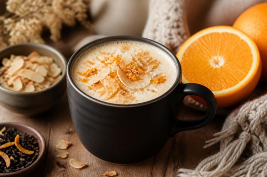 toasted coconut orange tea latte in a black mug with fresh orange